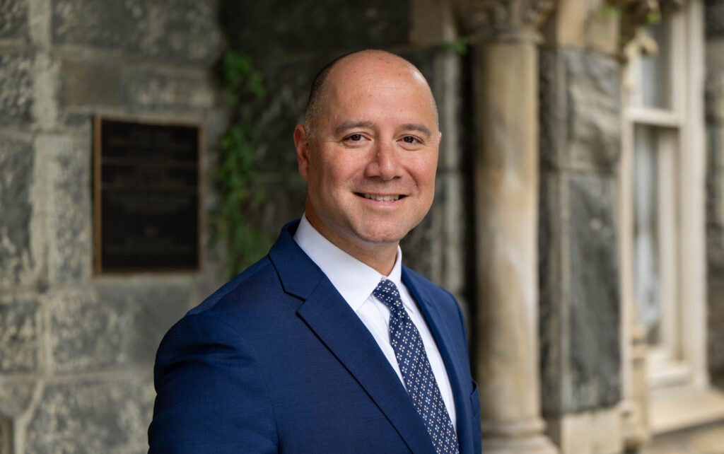 Headshot of Dave Green in front of a stone building called Healy Hall