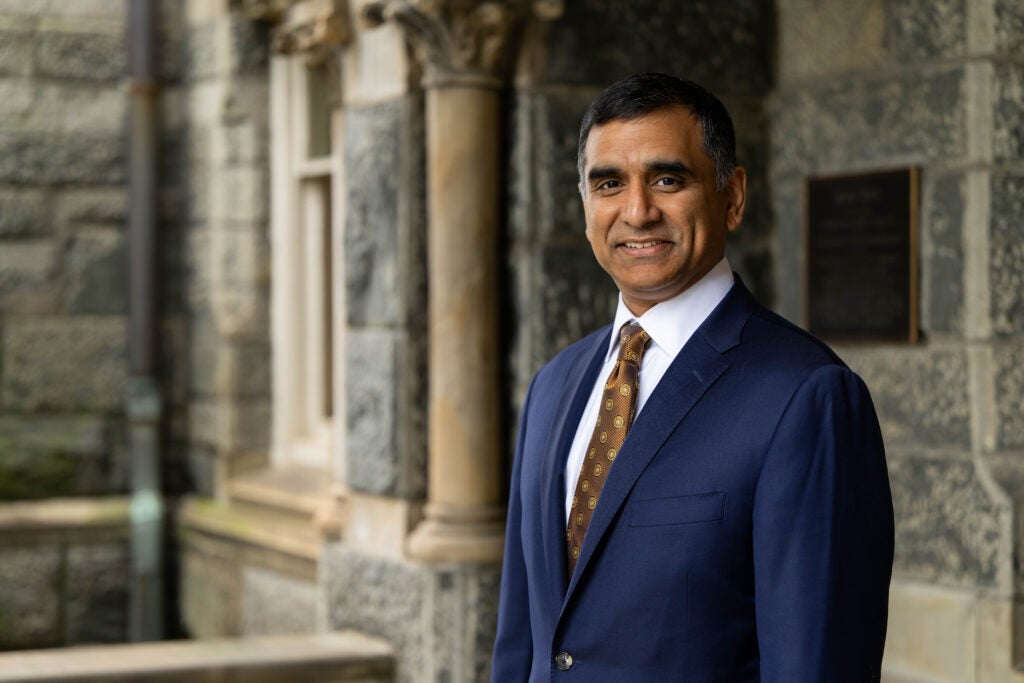 headshot of Hari Sastry, CFO, in front of a stone building called Healy Hall. Hari is wearing a suit and tie.