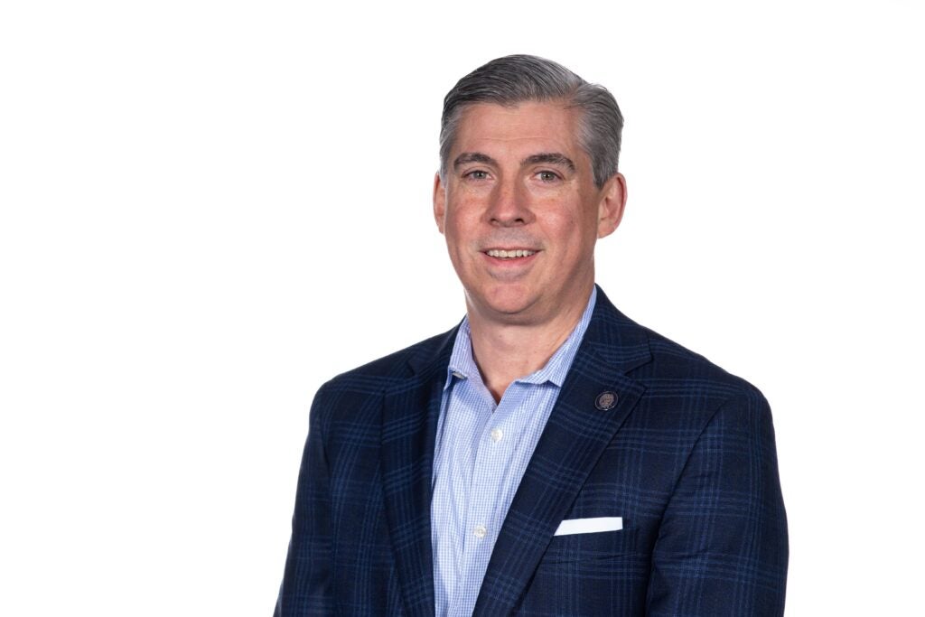 headshot of Marc Fournier smiling and wearing a blue suit