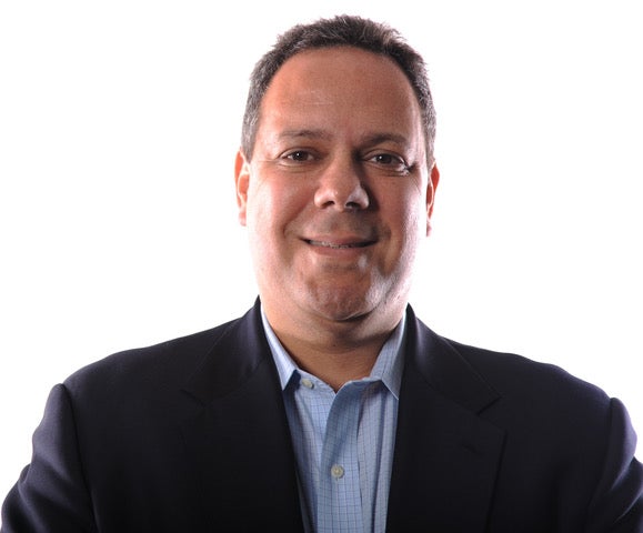 headshot of Eric wearing a blue shirt and black jacket