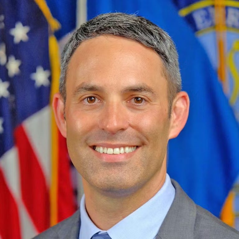 headshot of Josh who smiles and wears a suit